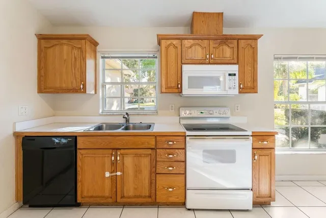 an empty room with a chandelier fan and windows