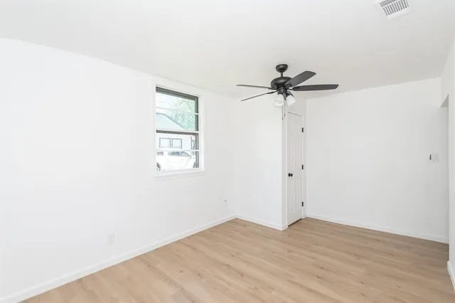 an empty room with a window and a ceiling fan