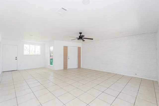 an empty room with windows and fan