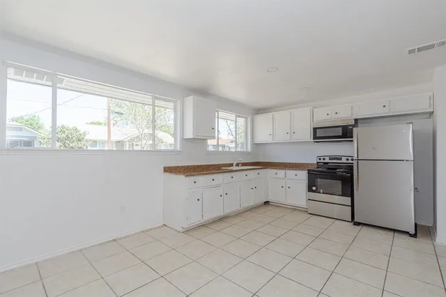 a large kitchen with white cabinets stainless steel appliances and a window