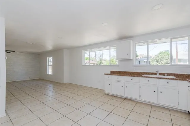 a view of a kitchen with white cabinets appliances a window and a sink