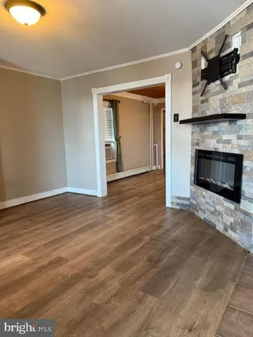 a view of an empty room with wooden floor fireplace and a window