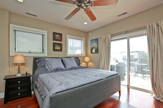 1255 West Addison Street, Unit 3 Chicago, IL 60613 - Photo 8 of 13 a bedroom with a large bed and a lamp on dresser