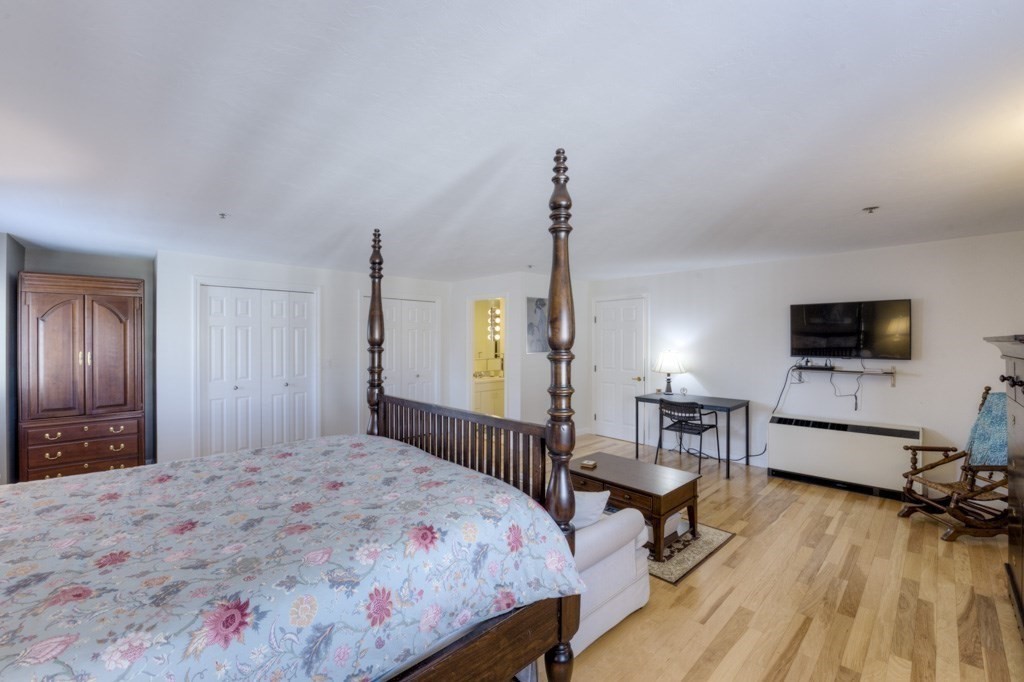 44 Elm Street, Unit 501 Worcester, MA 01609 - Photo 32 of 41 a bedroom with a bed a mirror on dresser and a wooden floor