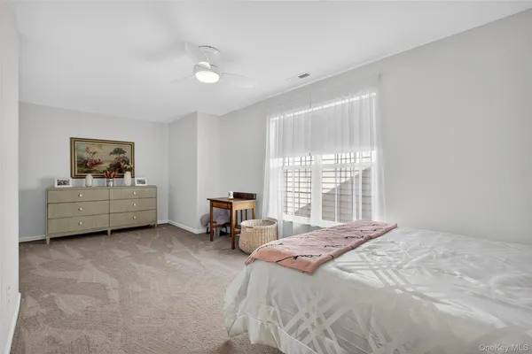 a spacious bedroom with a bed a couch and window