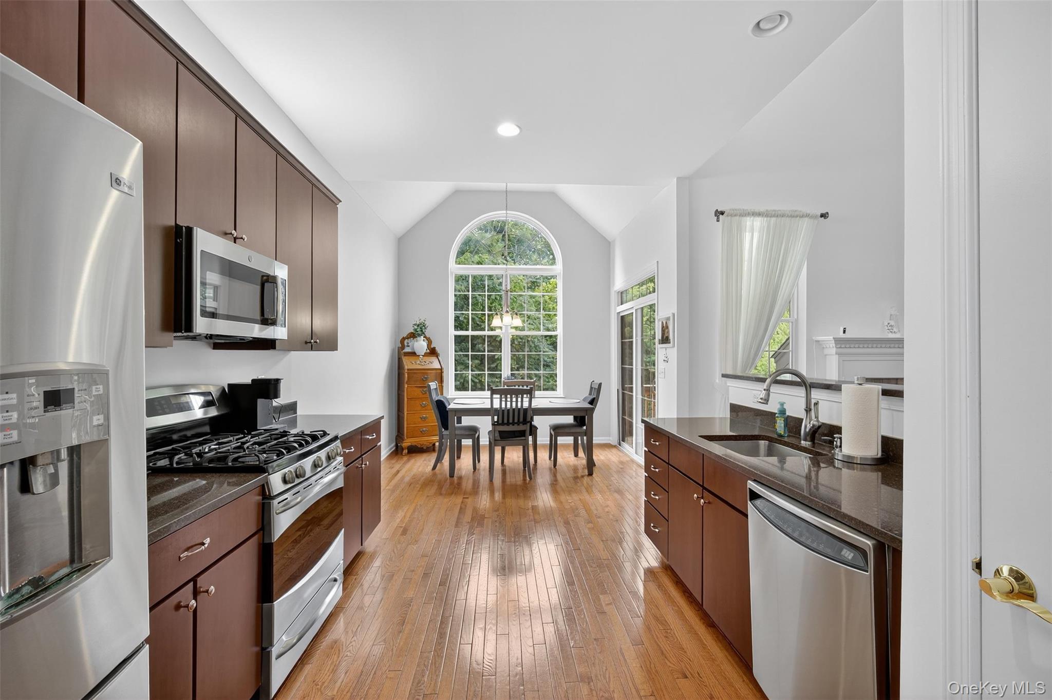 167 Stony Brook Road Fishkill, NY 12524 - Photo 7 of 42 Kitchen with stainless steel appliances, dark stone counters, light wood-style floors, dark brown cabinetry, and vaulted ceiling