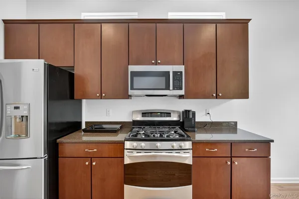 a kitchen with granite countertop a refrigerator stove and microwave
