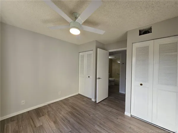 an empty room with wooden floor and a ceiling fan