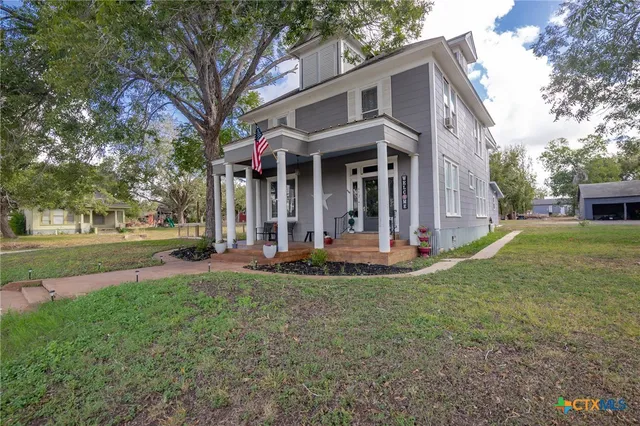 a view of a white house with a big yard and large trees