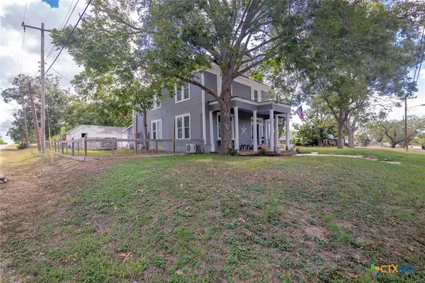 a view of a house with a yard and large tree