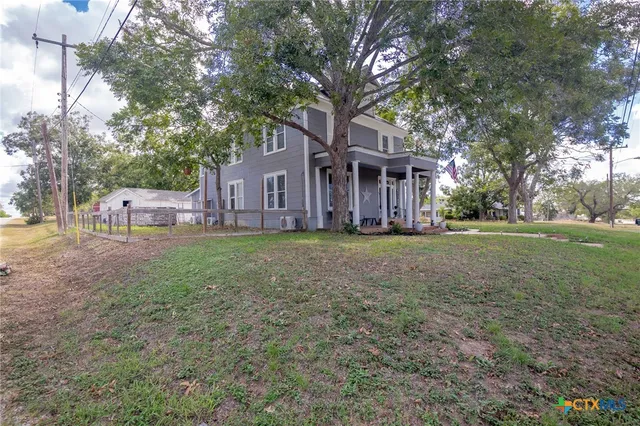 a view of a house with a yard and large tree
