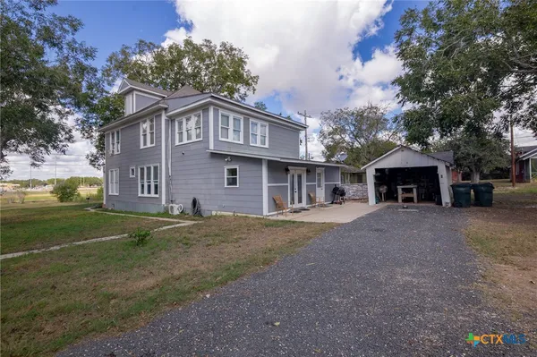 a view of a house with a yard and large tree
