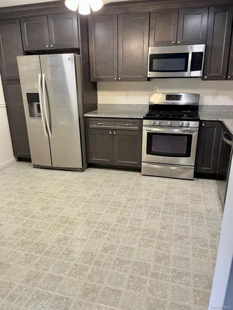 a kitchen with granite countertop a refrigerator and a stove top oven