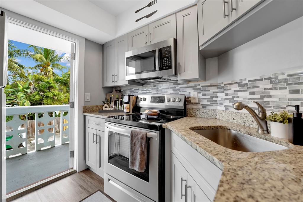 2161 Northeast 42nd Court, Unit 215 Lighthouse Point, FL 33064 - Photo 14 of 50 a kitchen with stainless steel appliances granite countertop a sink a stove and a microwave with wooden floor