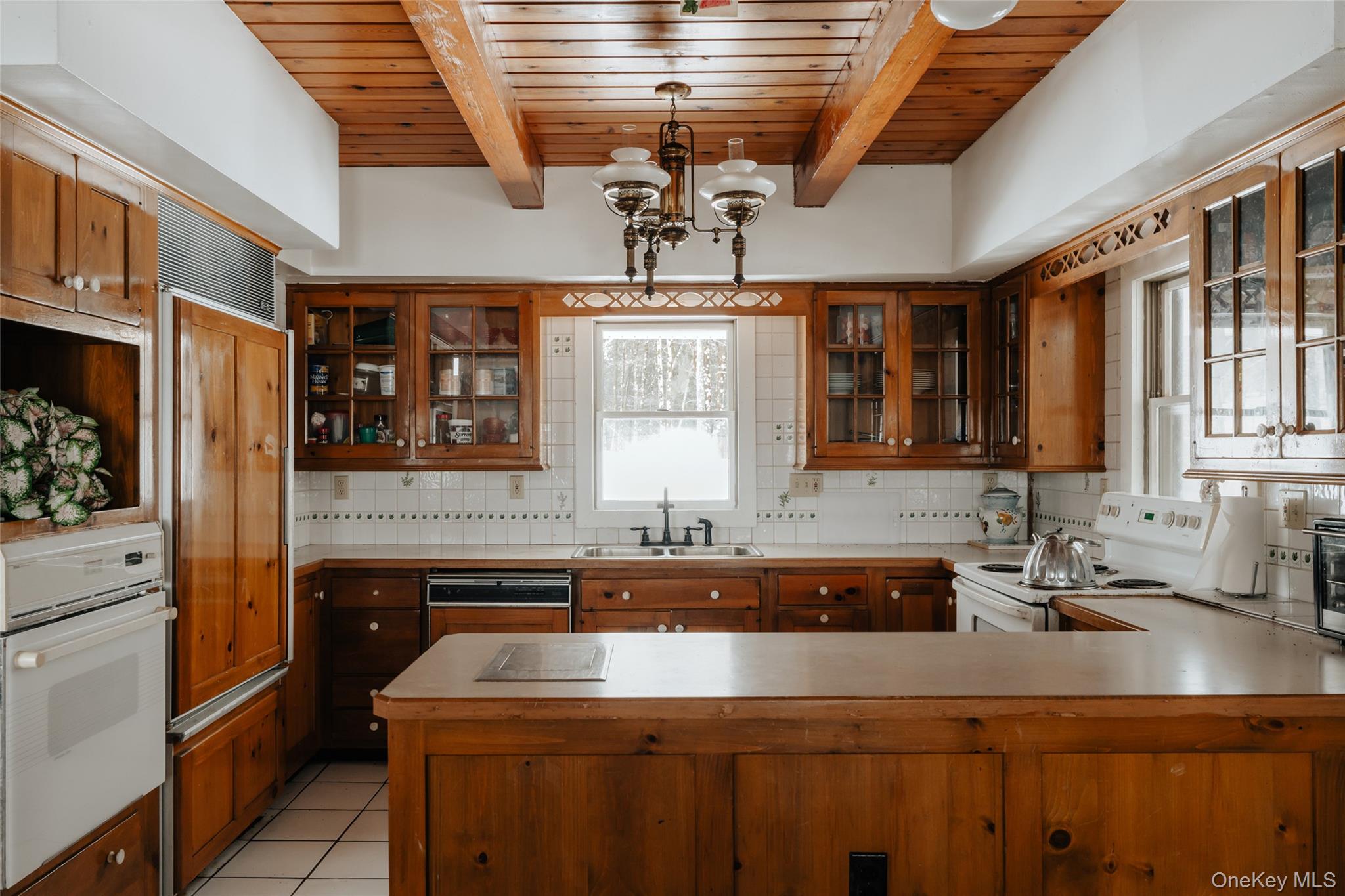 26 Beckys Hill Road Loch Sheldrake, NY 12759 - Photo 33 of 50 Kitchen featuring backsplash, white appliances, brown cabinetry, hanging light fixtures, and a wooden ceiling with exposed beams
