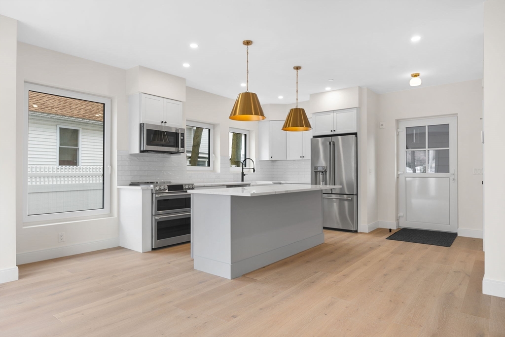 148 Myrtle Street, Unit 4 Melrose, MA 02176 - Photo 4 of 35 a kitchen with stainless steel appliances kitchen island granite countertop a refrigerator a sink a stove and oven