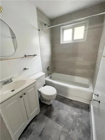 a bathroom with a toilet sink vanity tub and mirror