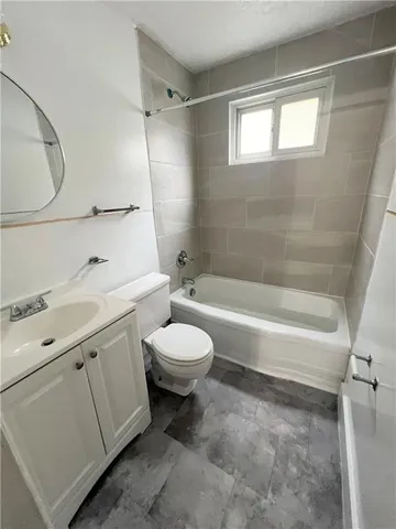 a bathroom with a toilet sink vanity tub and mirror