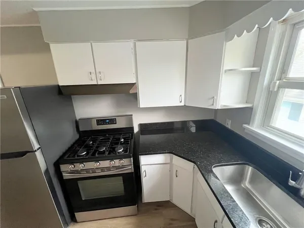 a kitchen with granite countertop a stove sink and cabinets