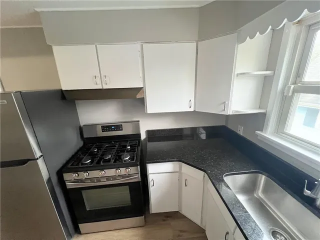 a kitchen with granite countertop a stove sink and cabinets