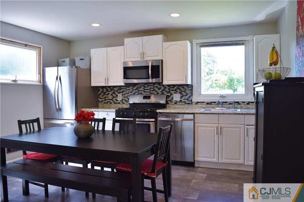 24 North Pennington Road New Brunswick, NJ 08901 - Photo 11 of 47 a kitchen with stainless steel appliances granite countertop a stove a refrigerator a sink a dining table and chairs with wooden floor