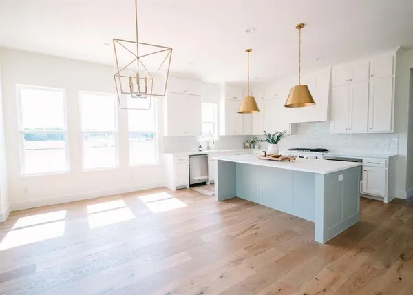 a view of a kitchen with kitchen island a window a sink a center island and a window