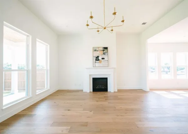 an empty room with windows fireplace and wooden floor