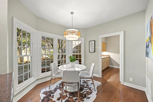 a dining room with wooden floor a chandelier a glass table and chairs