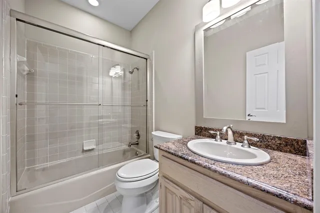 a bathroom with a granite countertop sink a toilet and shower