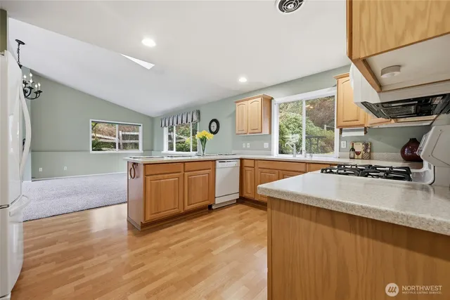 a large kitchen with stainless steel appliances granite countertop a sink and a stove next to a large window
