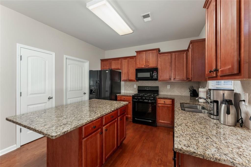 113 Tyson Woods Road Acworth, GA 30102 - Photo 15 of 37 a kitchen with stainless steel appliances granite countertop a stove top oven a sink dishwasher and a refrigerator with wooden floor