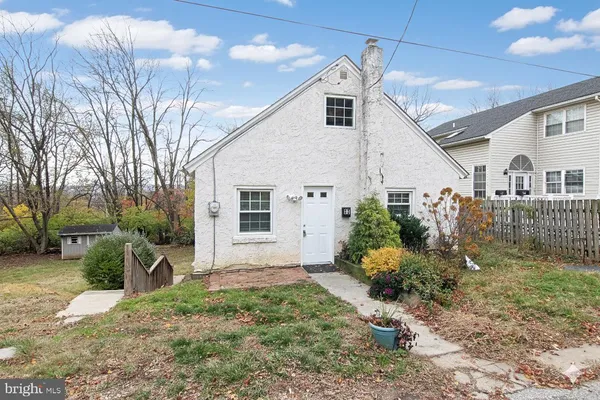 a view of a white house next to a yard with potted plants