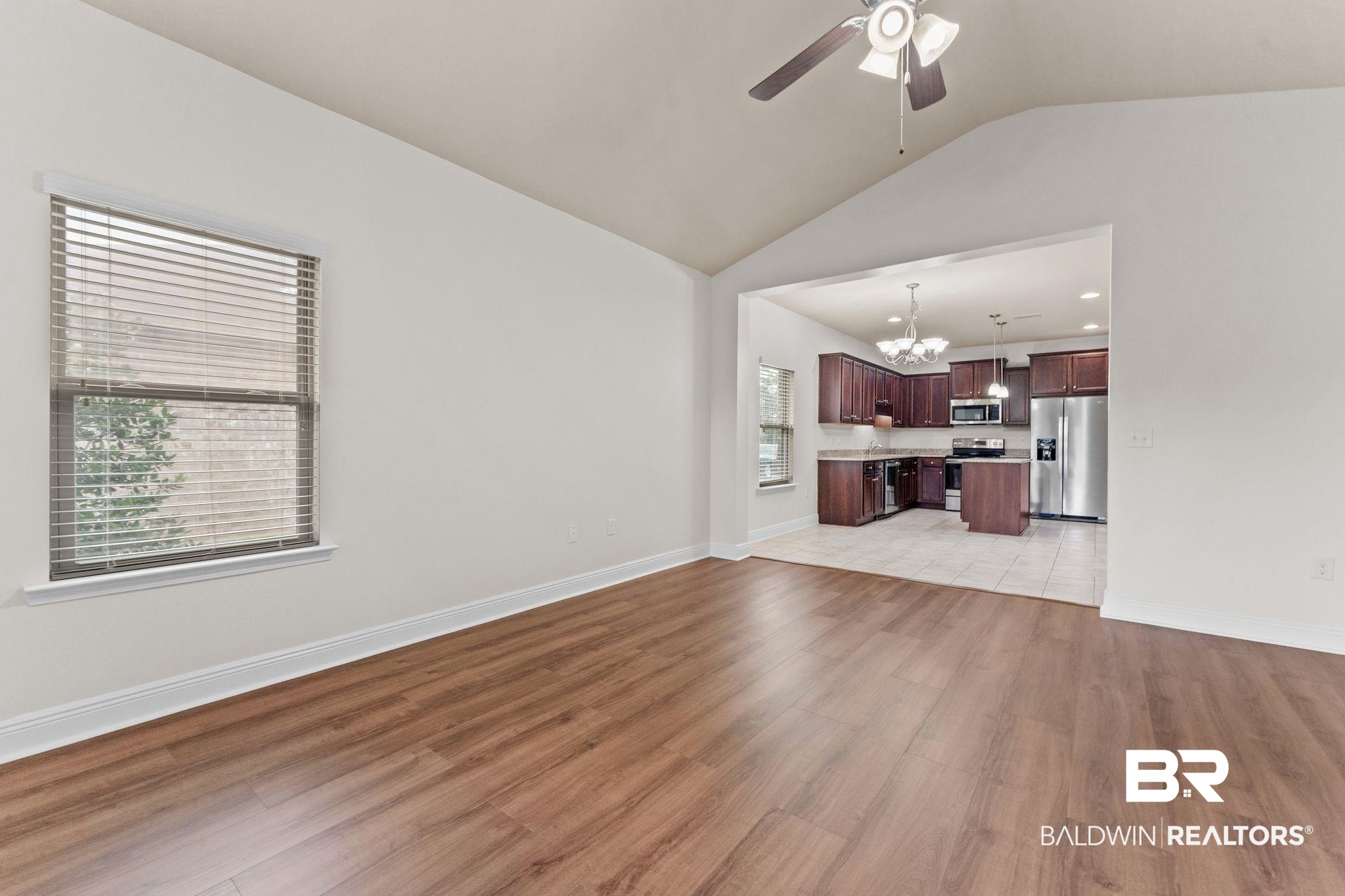 1464 Surrey Loop Foley, AL 36535 - Photo 10 of 24 Unfurnished living room featuring a chandelier, lofted ceiling, a ceiling fan, and light wood-style flooring