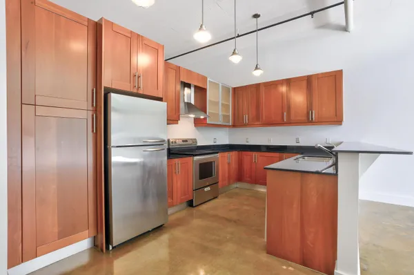 a kitchen with stainless steel appliances granite countertop a refrigerator a sink and a stove