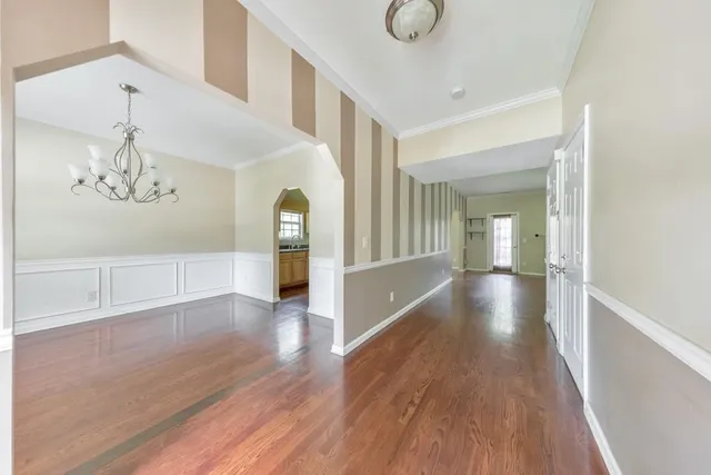 a view of a hallway with wooden floor and chandelier