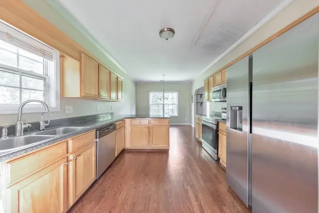 a large kitchen with kitchen island granite countertop a large window a sink and stainless steel appliances