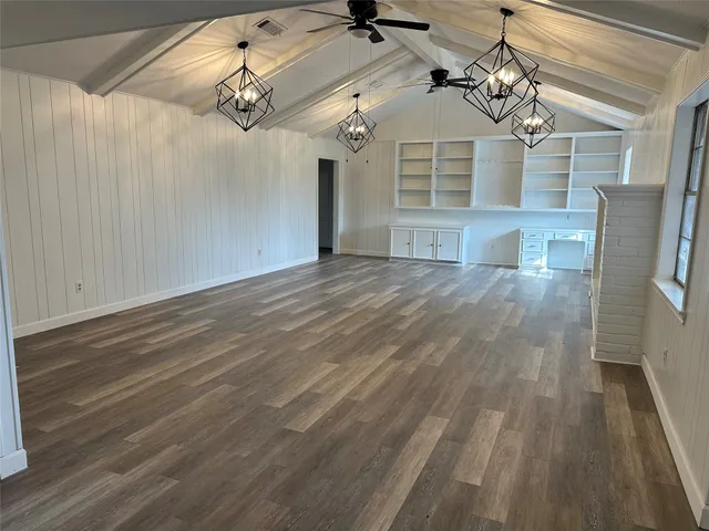 a view of a big room with wooden floor and windows