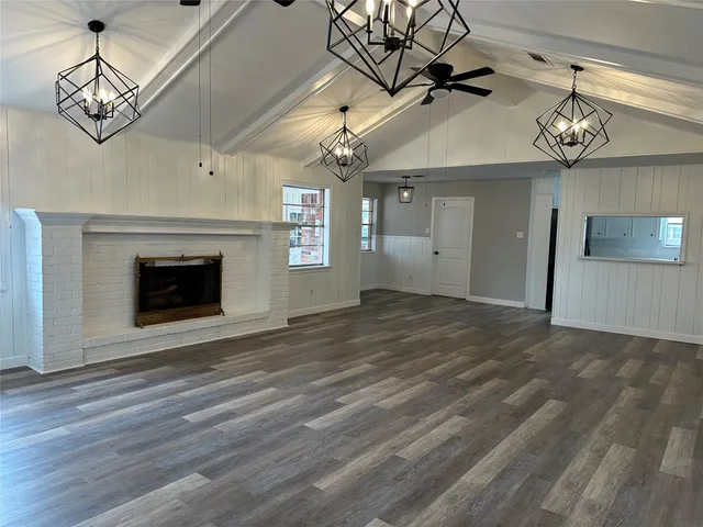 a view of an empty room with a fireplace and chandelier fan