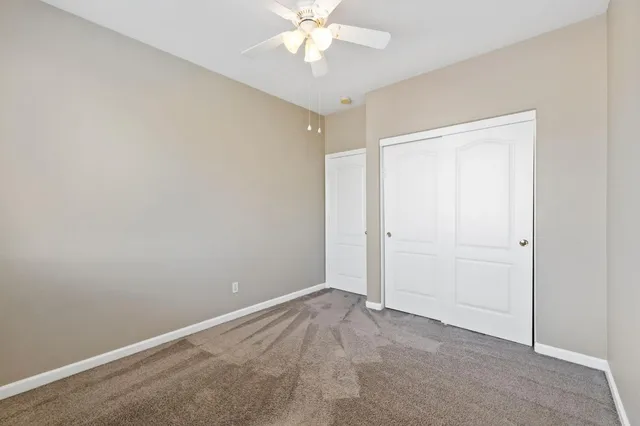 an empty room with closet and a chandelier fan
