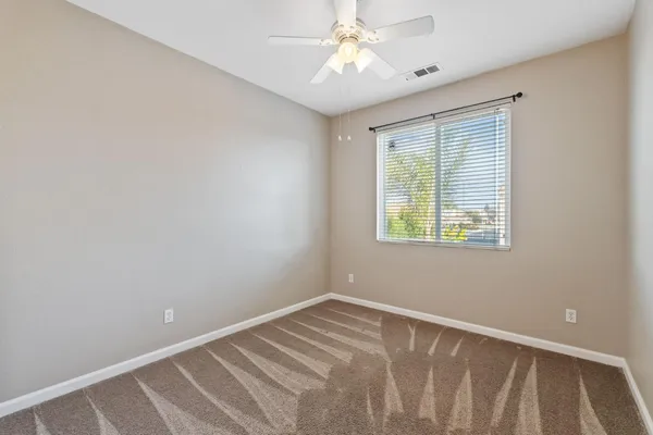 an empty room with closet and a chandelier fan