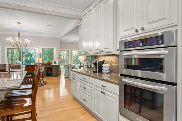 a kitchen with stainless steel appliances kitchen island granite countertop a stove a sink and white cabinets