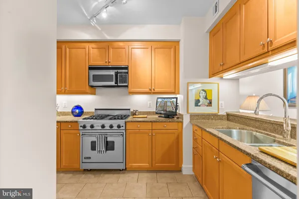a kitchen with stainless steel appliances granite countertop a stove a sink and a microwave