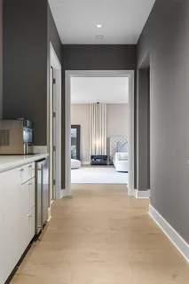 a view of a hallway to an empty room and kitchen