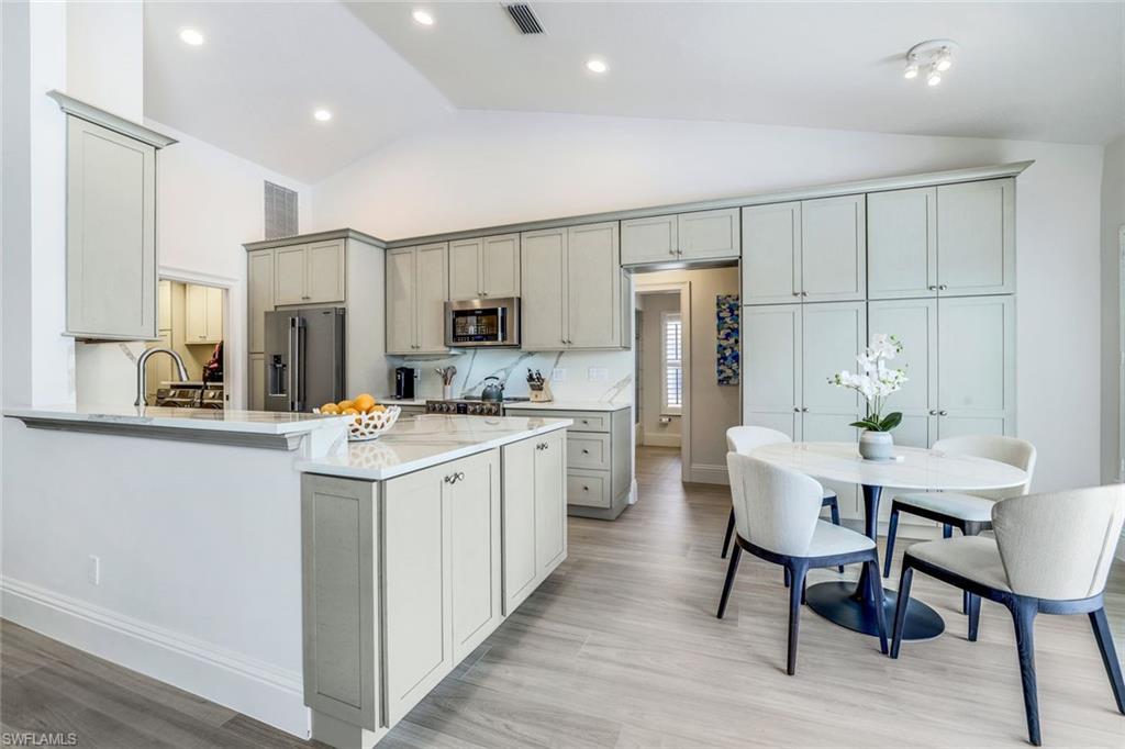 914 Marble Drive Naples, FL 34104 - Photo 12 of 50 a kitchen with stainless steel appliances white cabinets and wooden floor