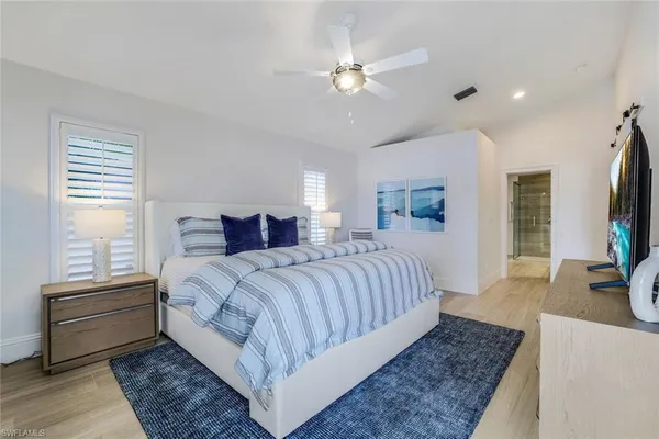 a bedroom with a large bed a flat tv screen and a dresser