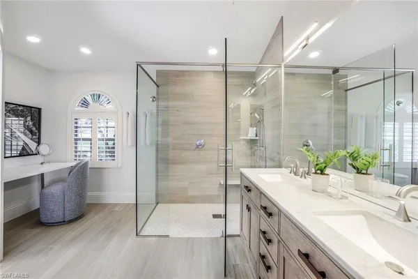 a bathroom with a double vanity sink a large mirror and shower