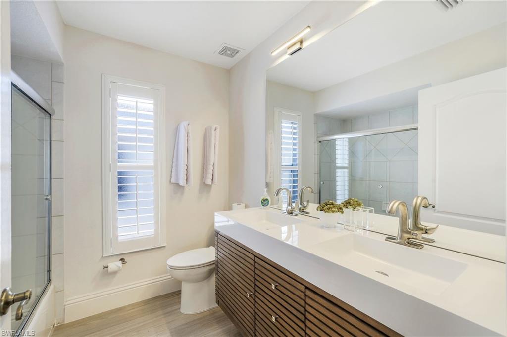 914 Marble Drive Naples, FL 34104 - Photo 24 of 50 a bathroom with a double vanity sink toilet and a mirror