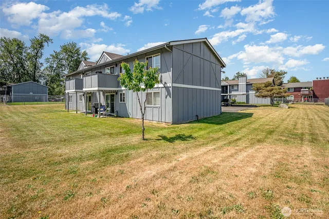 a view of a house with a yard and large tree