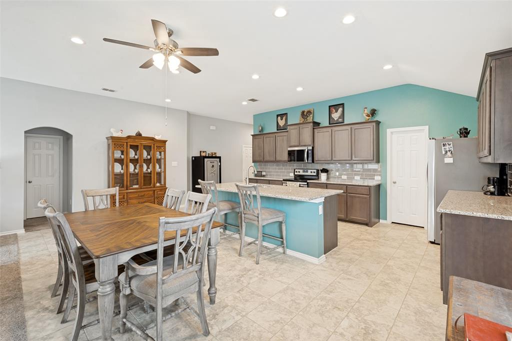 3905 Bridle Path Lane Sanger, TX 76266 - Photo 8 of 26 a kitchen with stainless steel appliances kitchen island granite countertop a table chairs and a refrigerator