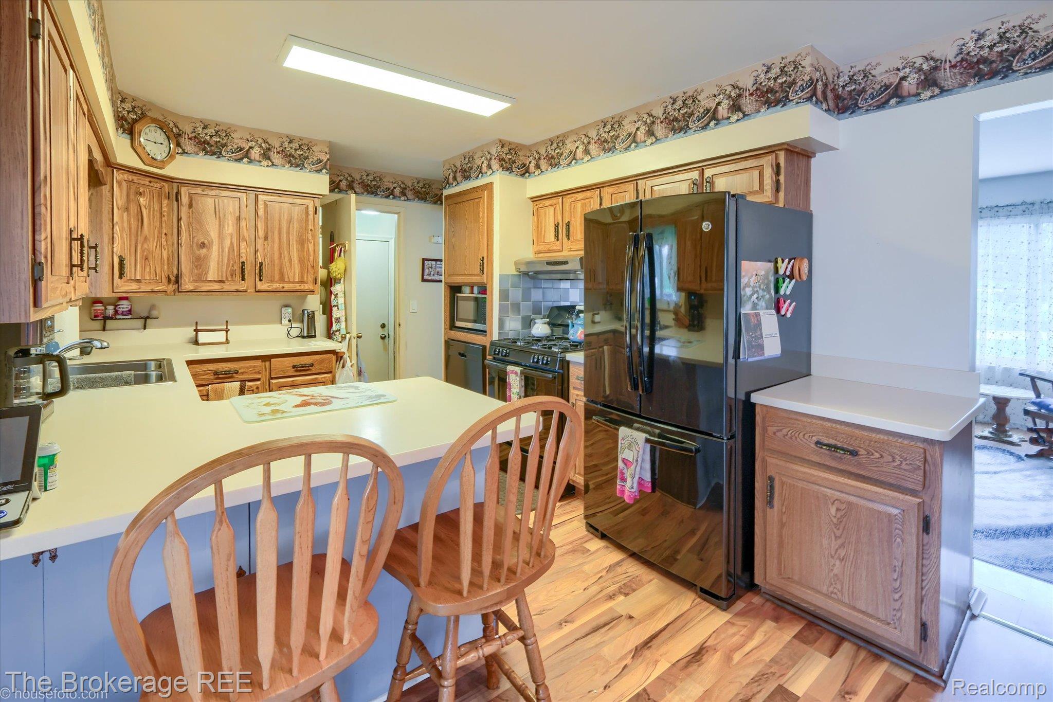 6129 East Lake Road Millington, MI 48746 - Photo 14 of 47 Kitchen featuring freestanding refrigerator, light countertops, tasteful backsplash, light wood-style flooring, and a peninsula